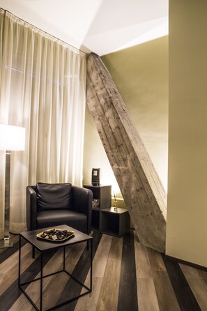 A modern room with a leather chair, a small table, and a wooden floor. - Serendipity Rooms (Milan)