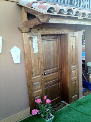 A wooden door with a decorative handle and a small sign on the wall beside it.