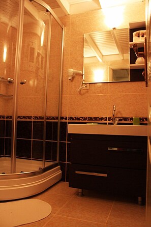 A bathroom with a glass-enclosed shower, a sink, and a mirror.