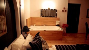 A bedroom with a large wooden headboard, a bathtub, and a bedside table with a lamp. - Villa Pine Garden (Sile)