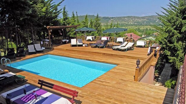 A wooden deck with a swimming pool, lounge chairs, and umbrellas. - Villa Pine Garden (Sile)