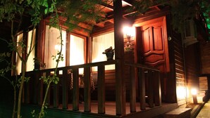 A wooden cabin with a porch, large windows, and a visible door. - Villa Pine Garden (Sile)