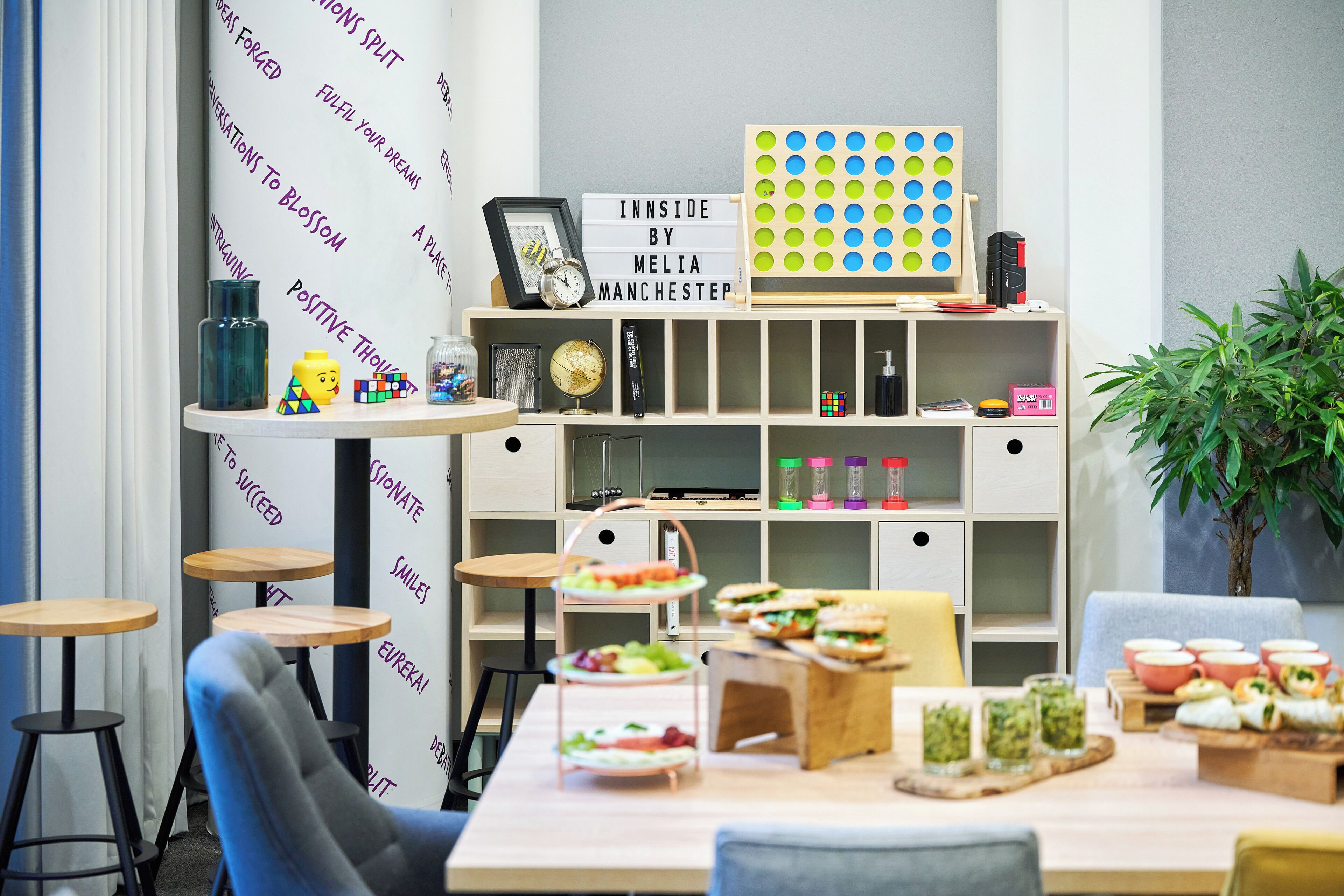 A modern room with a dining area, a bookshelf, and a wall with motivational phrases.