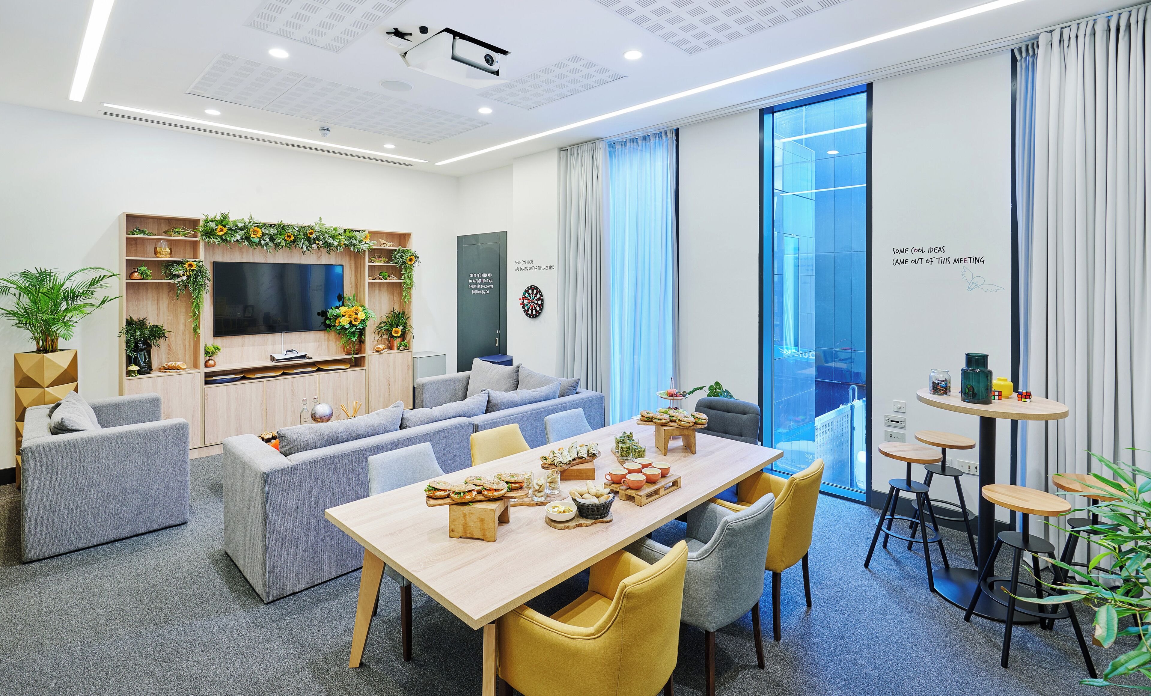 Una sala de reuniones moderna con una mesa larga, sofás y un mueble para televisión.