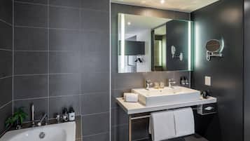 Un baño moderno con un lavamanos grande, espejo y bañera.