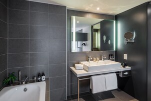 Un baño moderno con un lavamanos grande, espejo y bañera.