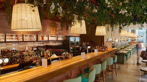 A bar area with a long counter, bar stools, and hanging lights.