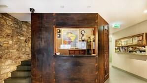 A reception area with a rustic wooden desk, a map, a clock, and a small shelf with books. - Okako Hotel (San Sebastián)