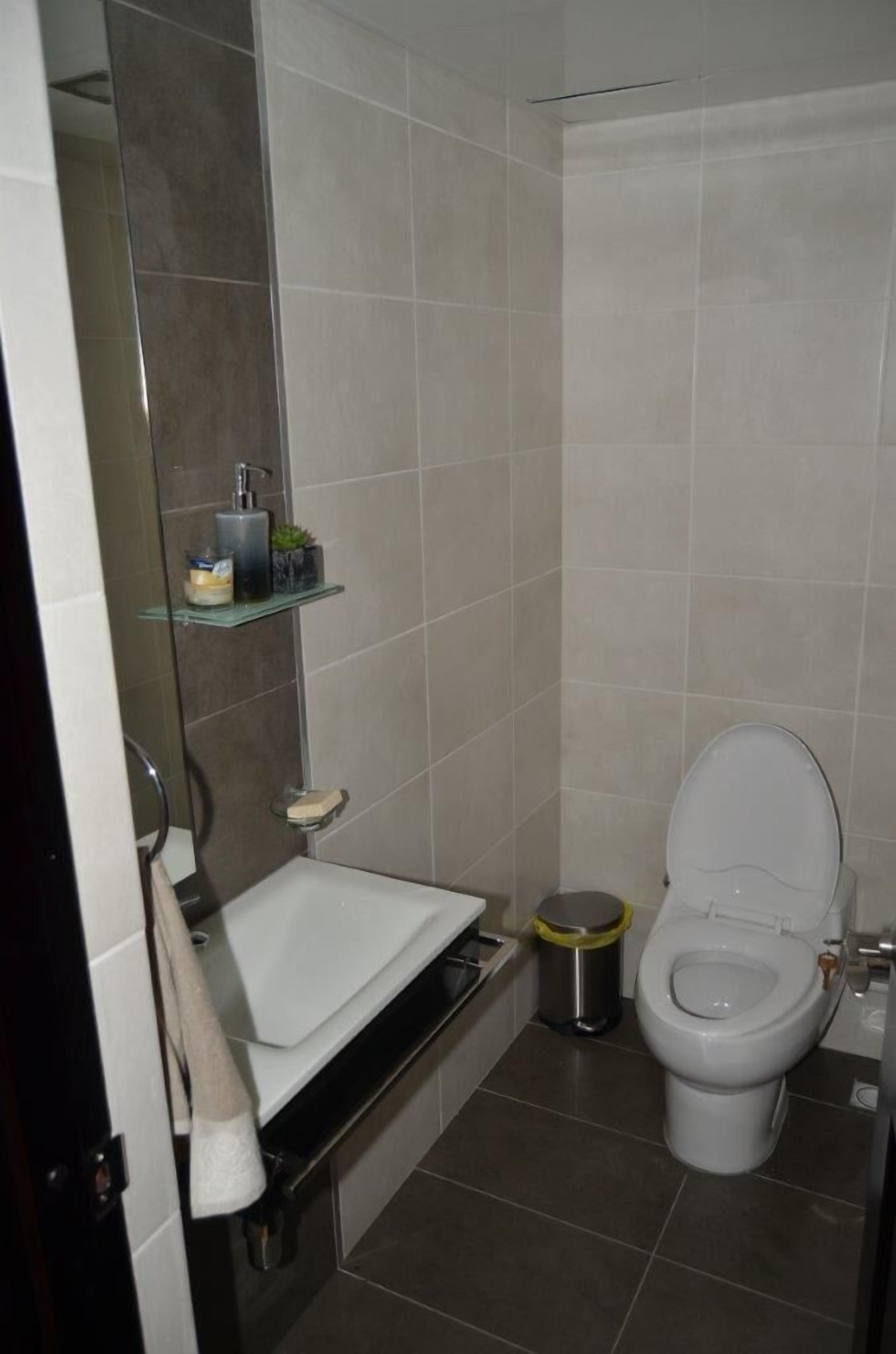 Un bany amb vàter blanc, un lavabo i una zona de dutxa.