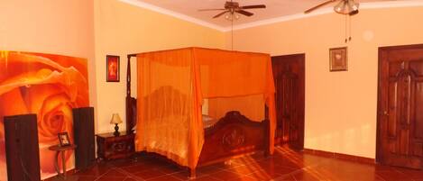 Una habitación con una cama con dosel, muebles de madera y un ventilador de techo.