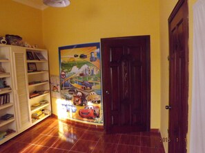 A room with a wooden door, a bookshelf filled with books and toys, and a colorful poster on the wall. - Four Bedroom Villa with Private Pool, Ocean View (Sosúa)