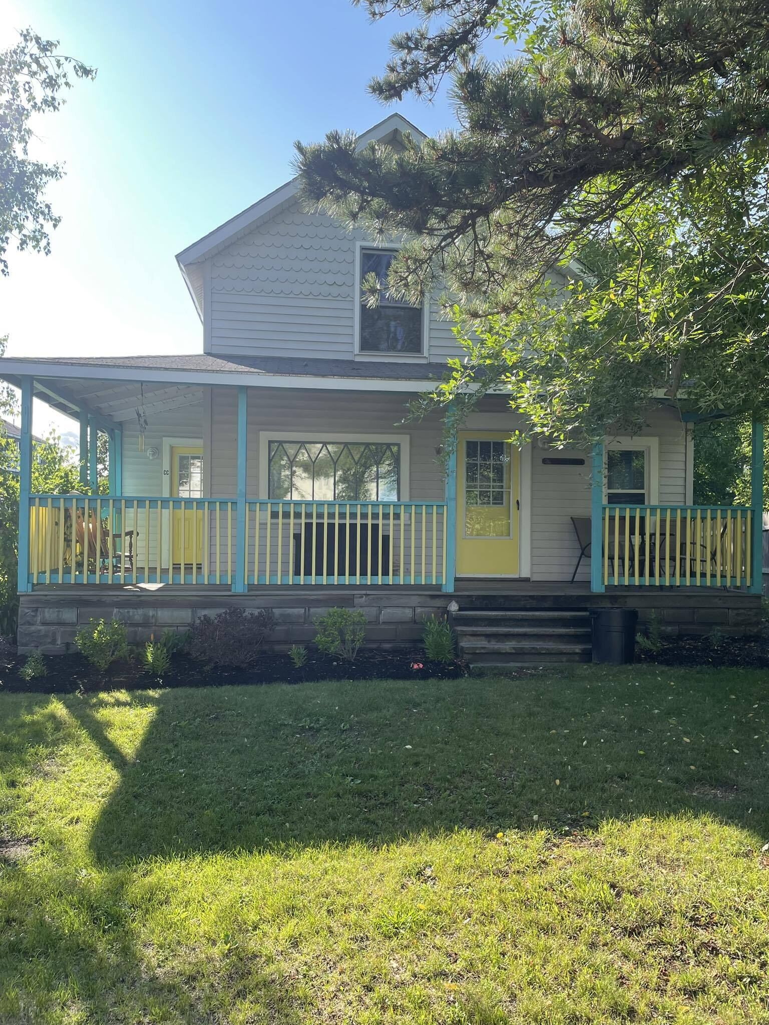 Una casa de dos pisos con un porche y un jardín pequeño.