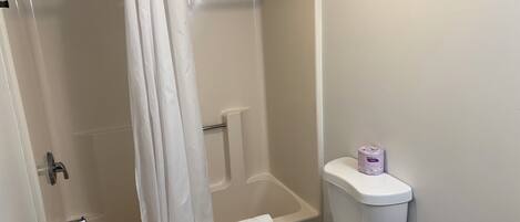 Un baño con bañera, inodoro y cortina de ducha.