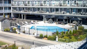 A hotel with a swimming pool, outdoor seating, and a multi-story building with balconies. - Grand Beach Inn (Old Orchard Beach)