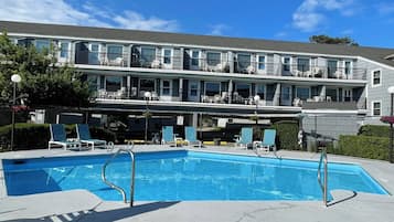 Een buitenzwembad, een verwarmd zwembad, ligstoelen bij het zwembad