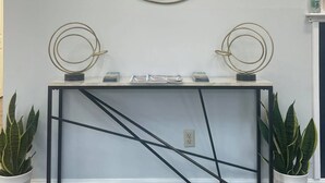 A modern console table with a mirror above it, flanked by two decorative circular mirrors. - Grand Beach Inn (Old Orchard Beach)