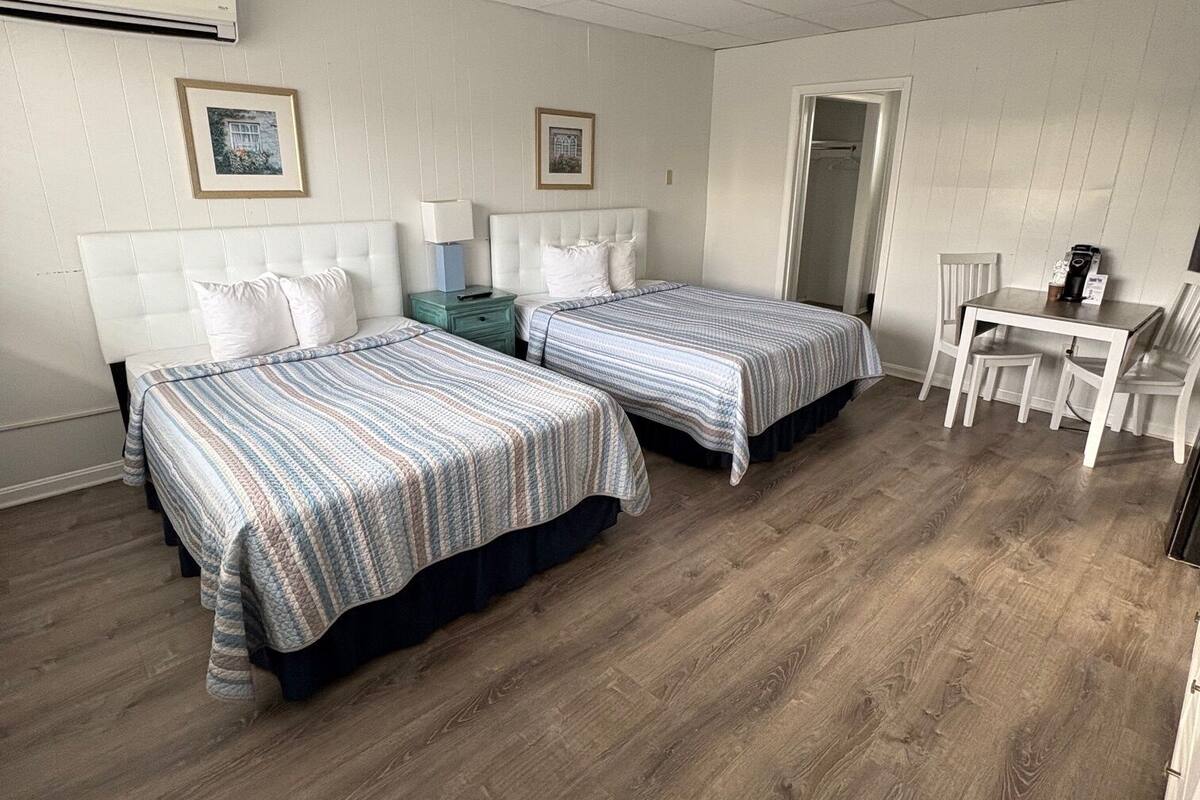 A hotel room with two beds, a desk, and a chair.