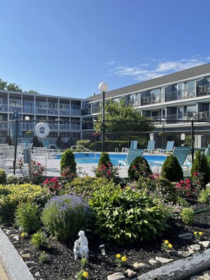 A pool area with a fence, a lifebuoy, and a statue of a child and adult.