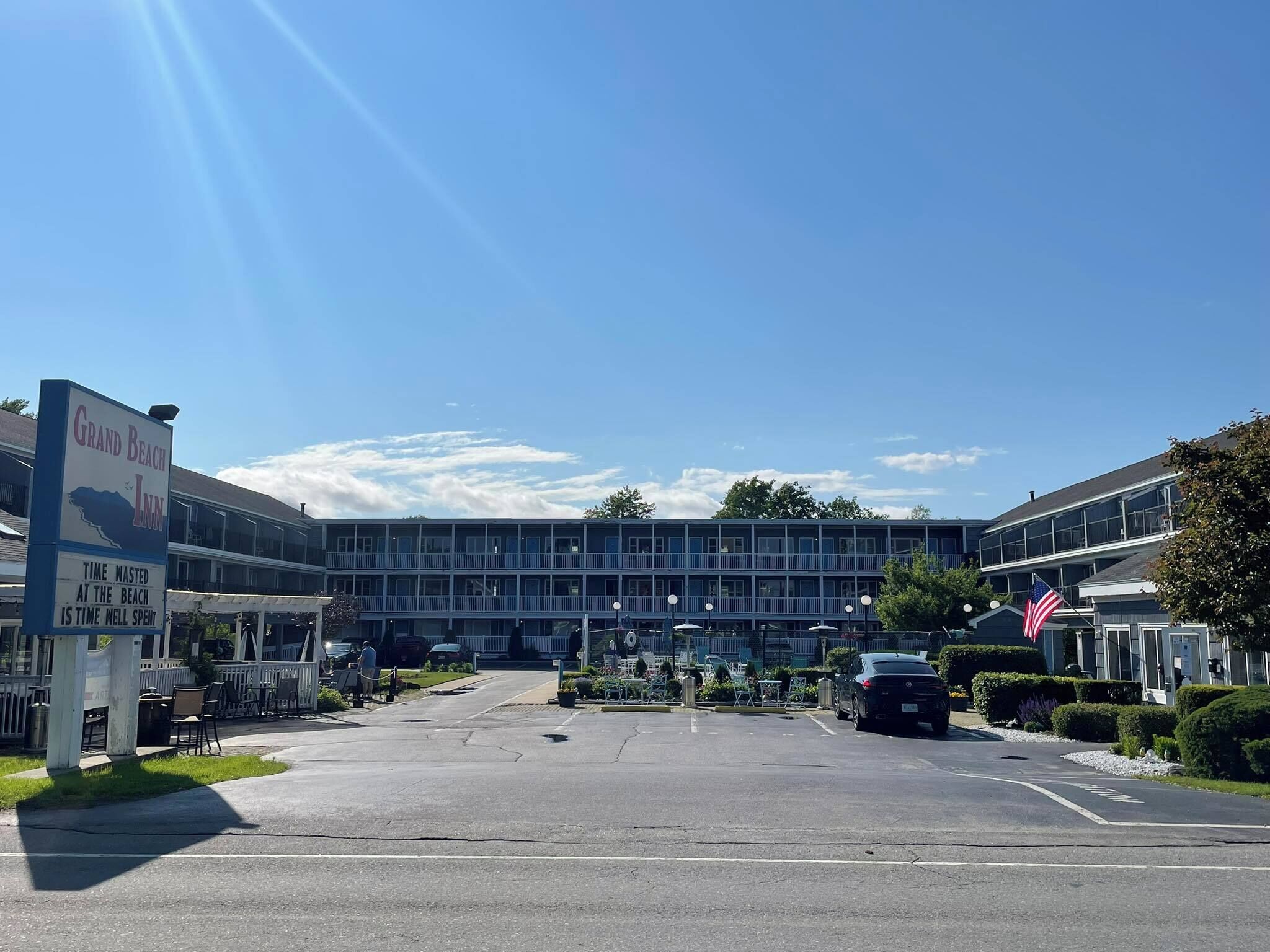 Un hotel con un letrero que dice "Grand Beach Inn" y un eslogan "El tiempo perdido en la playa es tiempo bien invertido".