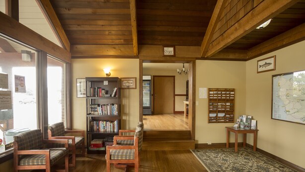 A cozy room with wooden furniture, a bookshelf, and a map on the wall. - The Forks Motel (Forks)
