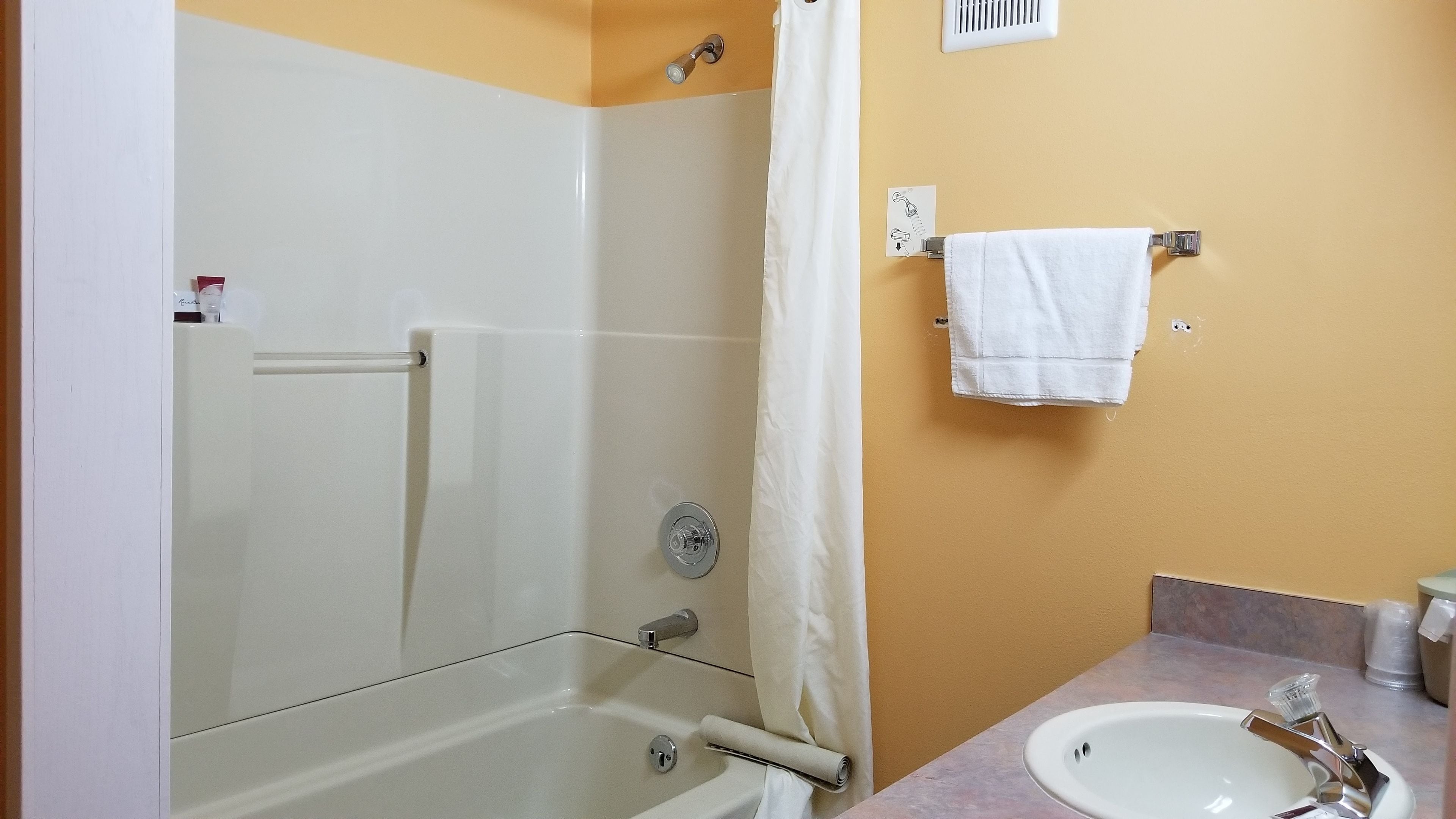 Une salle de bain avec une douche à parois de verre, un lavabo blanc et un porte-serviettes.