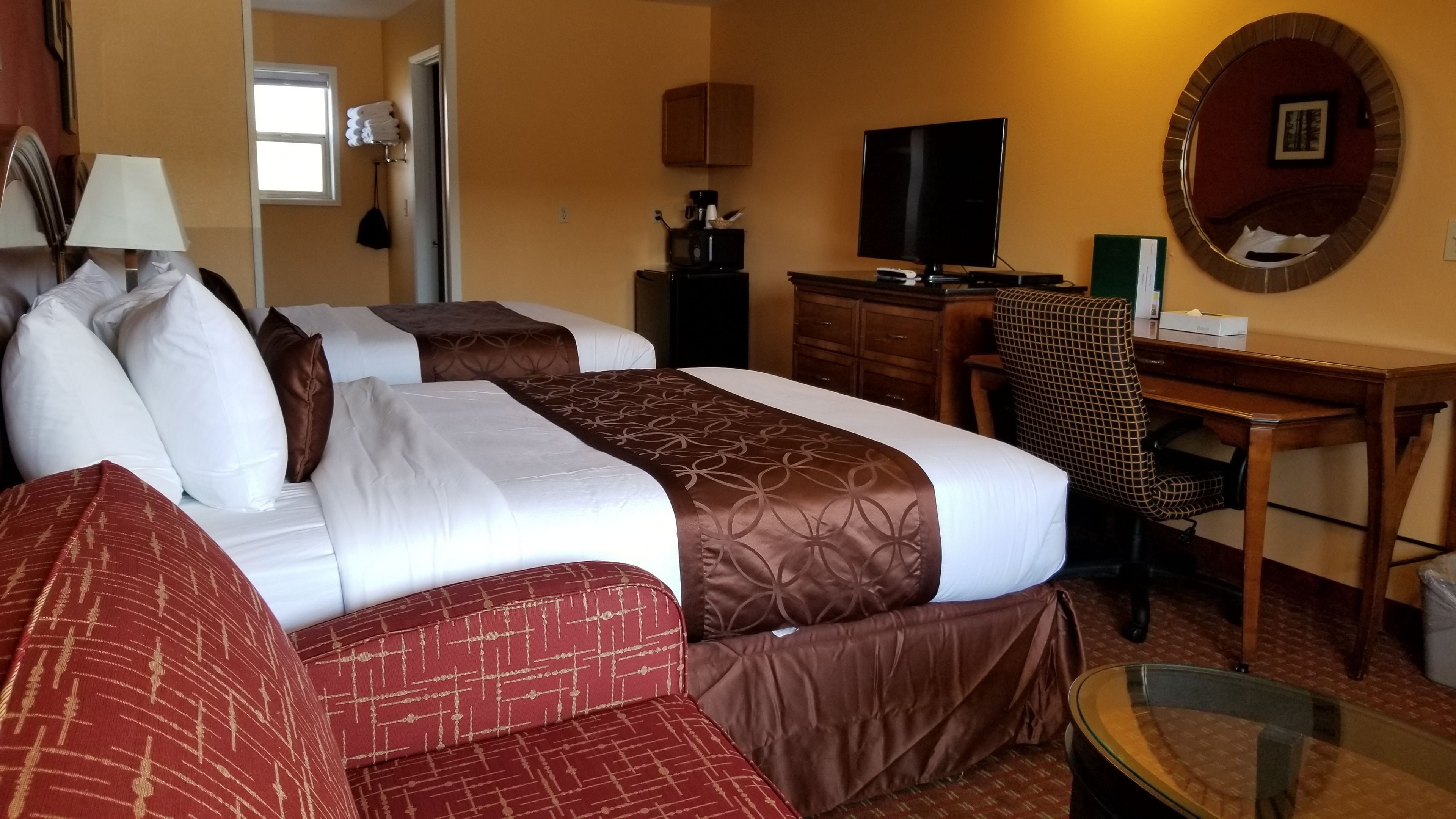 A hotel room with a bed, a desk, a television, and a mirror.