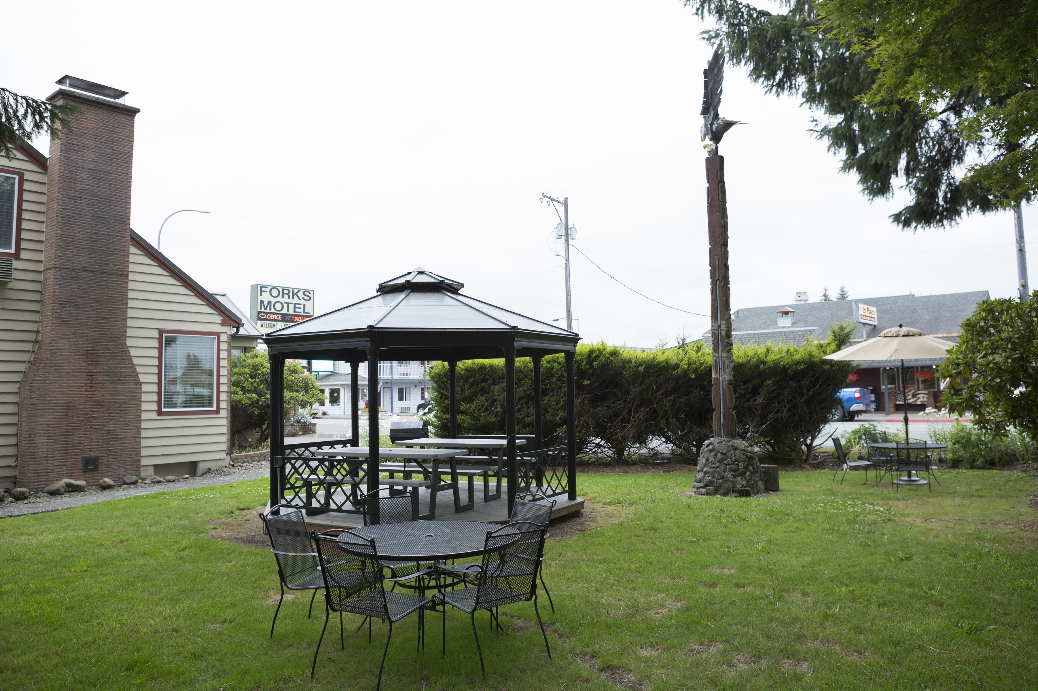 A gazebo with a table and chairs in a backyard.