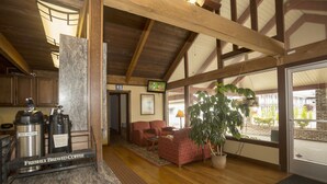 A spacious living area with a fireplace, a coffee station, and a large window offering a view of the outside. - The Forks Motel (Forks)