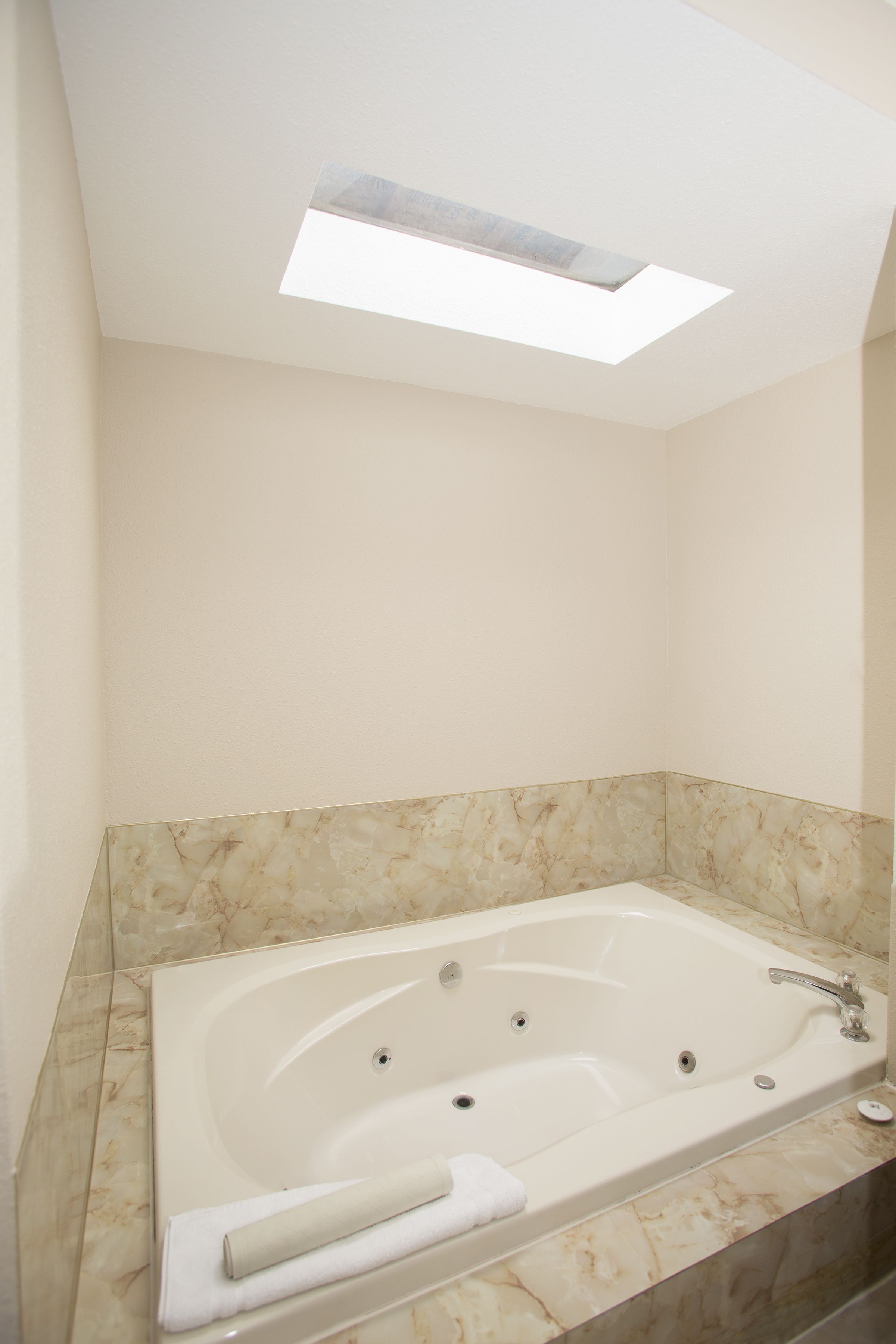 A modern bathroom with a freestanding bathtub, marble walls, and a skylight.