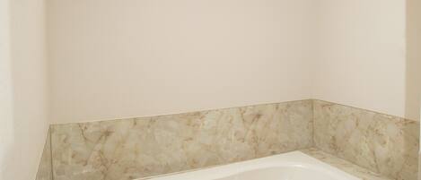 A modern bathroom with a freestanding bathtub, marble walls, and a skylight.