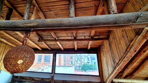 Un plafond en bois rustique avec des poutres apparentes et un luminaire tressé.
