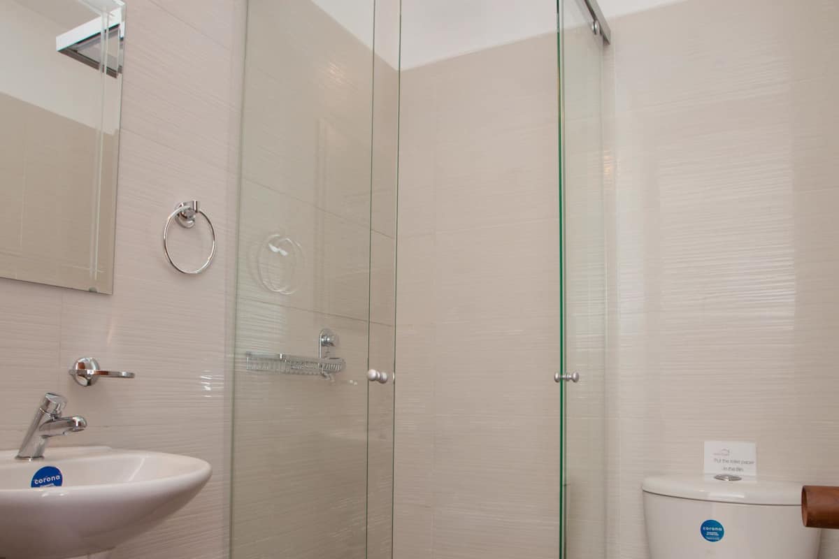 A bathroom with a glass-enclosed shower, a white sink, and a toilet.