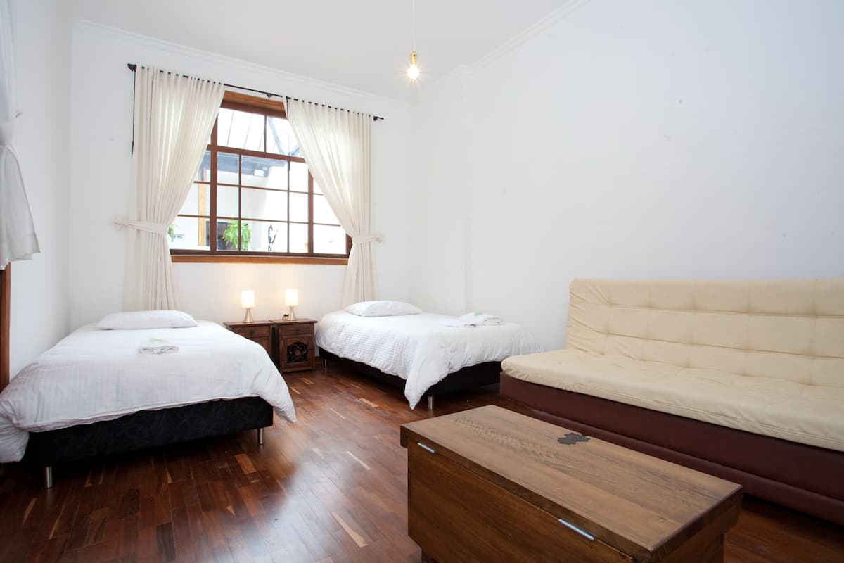 A room with two beds, a sofa, and a wooden table.