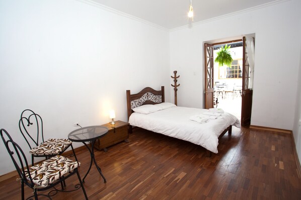 A bedroom with a wooden bed, a small round table with a chair, and a nightstand.