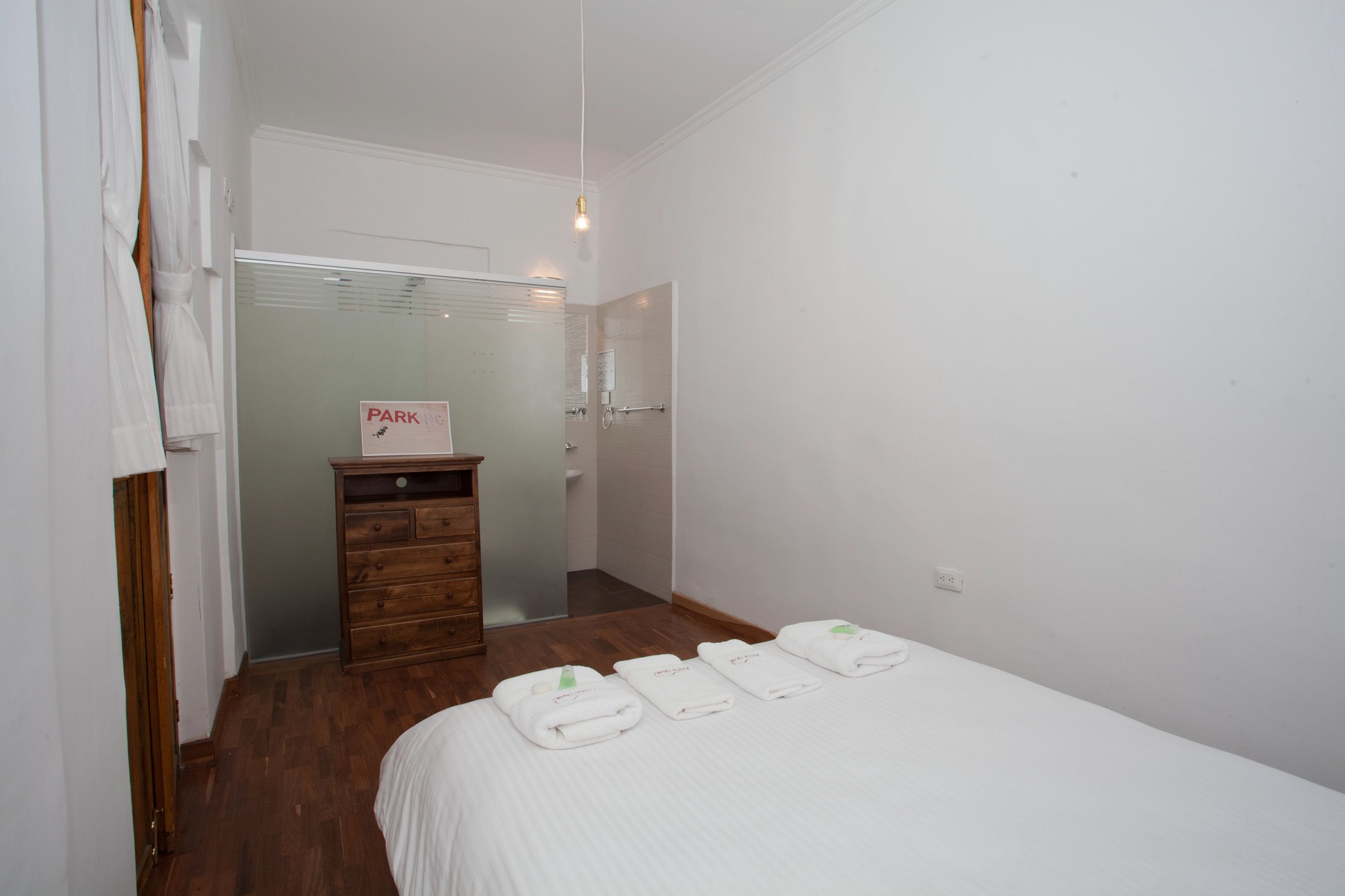 A hotel room with a bed, a wooden dresser, and a sign indicating parking.