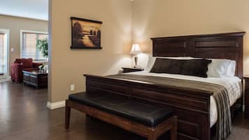 A bedroom with a large bed, a bench, a nightstand, a lamp, and a painting on the wall.