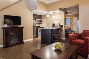 A modern kitchen with a microwave, stove, and dining area with a table and chairs. - The Castle at Swan Lake (Vernon)