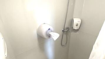 Un baño pequeño y moderno con inodoro, secamanos y ducha.