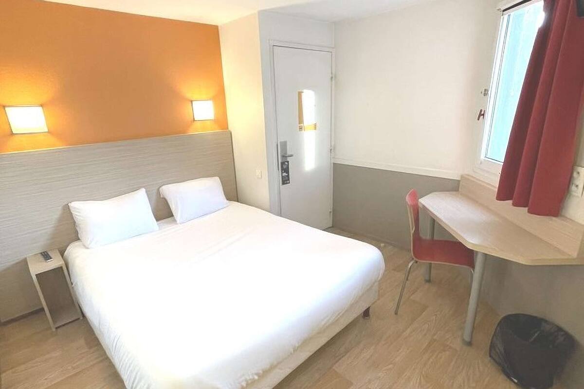 A hotel room with a large bed, bedside tables, a desk, and a chair.
