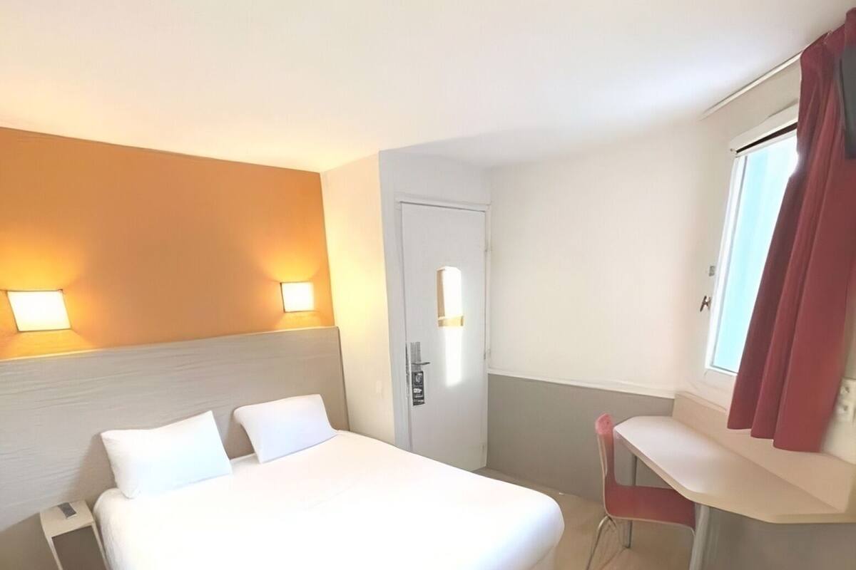 A hotel room with a large bed, bedside tables, a desk, and a chair.