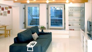 Una sala de estar moderna con un sofá verde oscuro, una mesita y un aparador de vidrio con botellas.