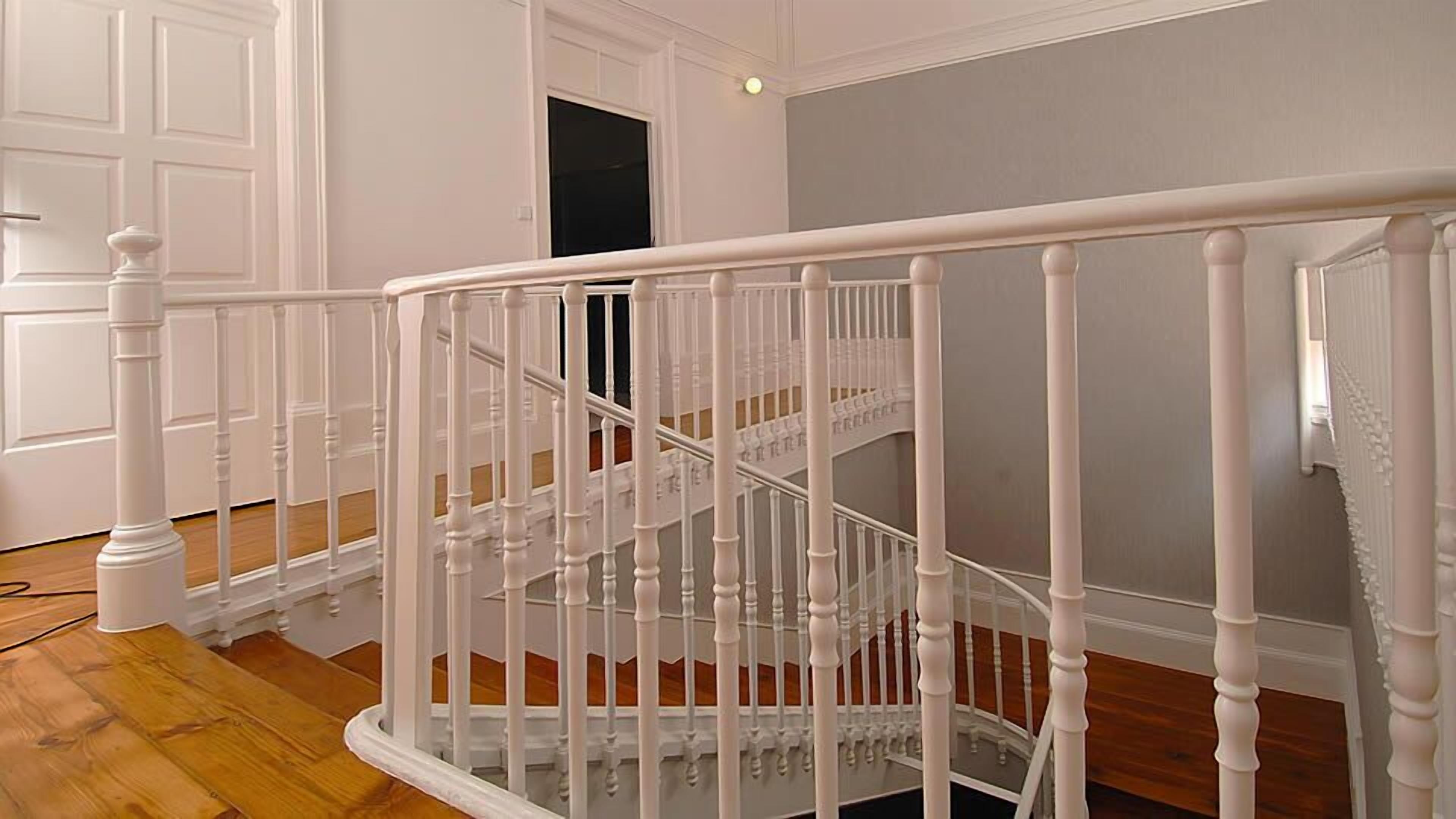 A white wooden staircase with a handrail, leading to an upper floor.