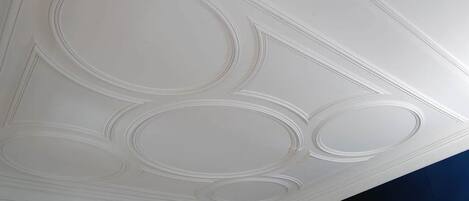 Un plafond orné de moulures décoratives et doté d’un éclairage encastré.