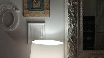 Una habitación con un espejo grande, una puerta blanca y una lámpara fijada a la pared.