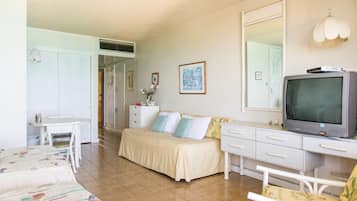 A bedroom with a bed, a desk, a television, and a dresser.