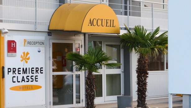 A hotel entrance with a yellow awning labeled "ACCUEIL" and a sign for "PREMIERE CLASSE HOTELS". - Premiere Classe Mâcon Sud (Chaintre)