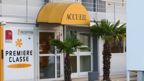 A hotel entrance with a yellow awning labeled "ACCUEIL" and a sign for "PREMIERE CLASSE HOTELS". - Premiere Classe Mâcon Sud (Chaintre)