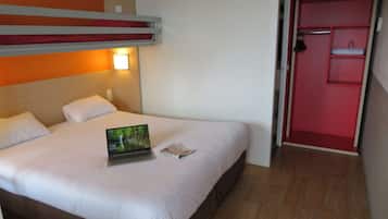 Una habitación de hotel con una cama, una laptop y una revista sobre la cama.
