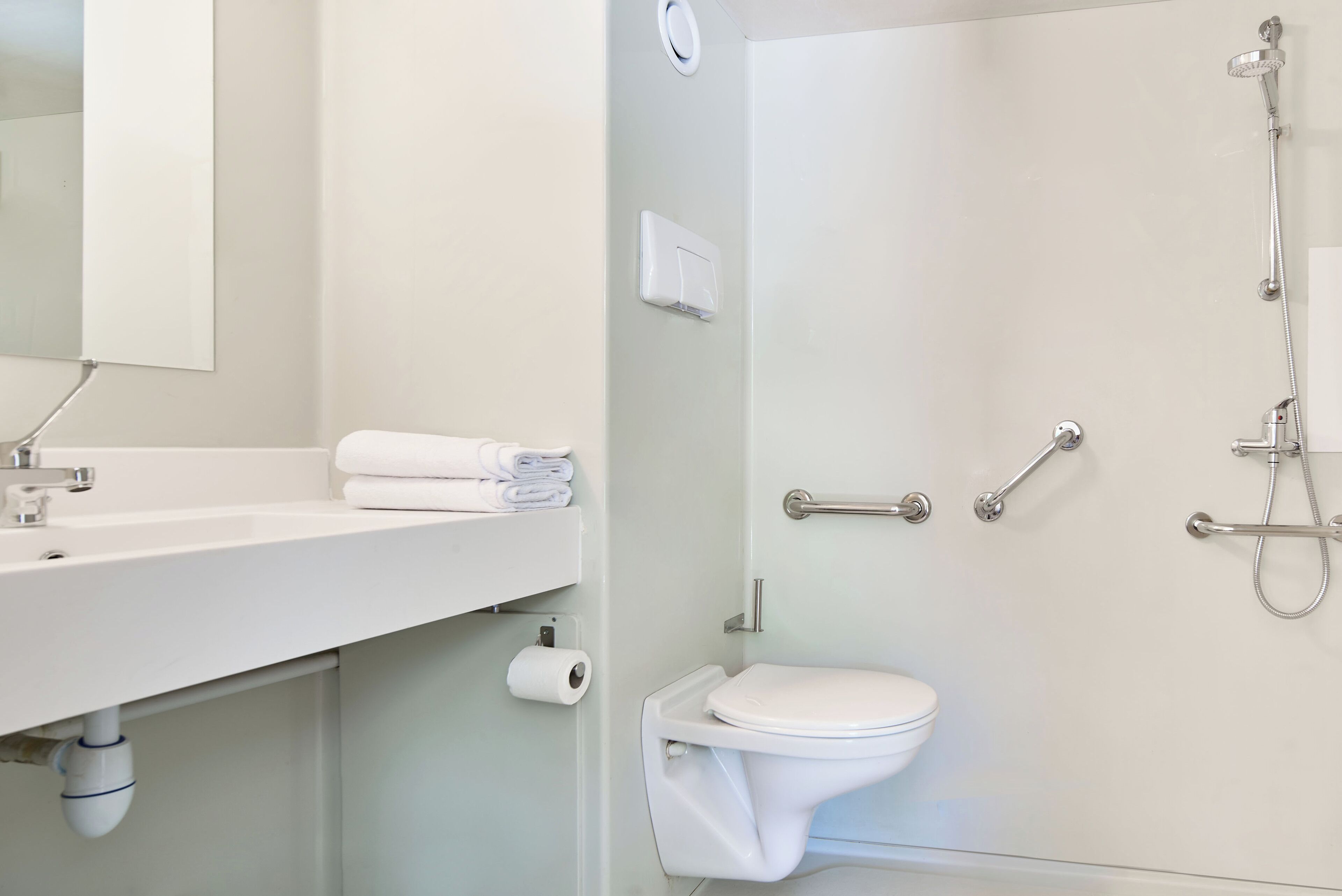 Une salle de bain moderne avec un lavabo, des toilettes et une douche, le tout de couleur blanche.