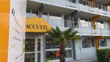 A hotel with a yellow sign reading "ACCUEL" and a balcony.